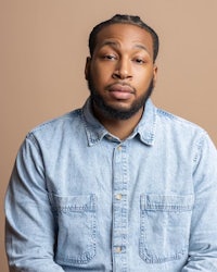 a black man in a denim shirt with dreadlocks